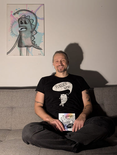 Tom Rechl mit einem FLOSSEN WEG!-Heftexemplar vor einem Bild von Dita @baerjungfrau Sommerauer